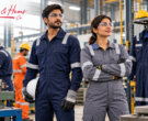Factory workers wearing navy and grey industrial coveralls with reflective strips, made by Curves & Hems, India